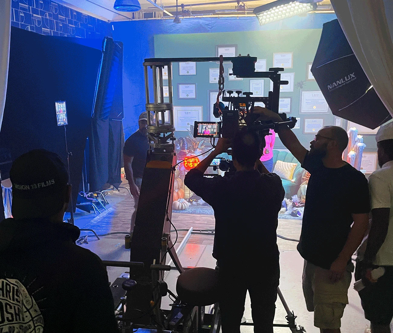 Studio set in 2023, with a camera crew on a jib working in front of a lit backdrop